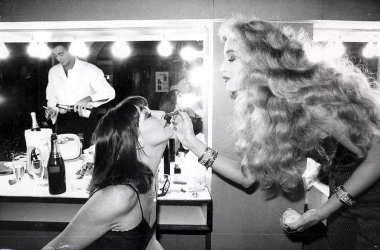 Jerry Hall touching up Angelica Huston, lipstick, champagne, repeat.